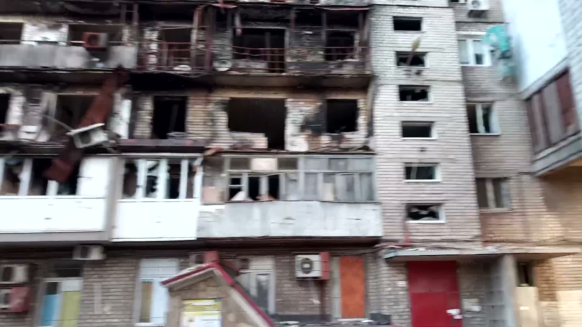 104 courtyard — close-range burnt facade, sheared balcony rail