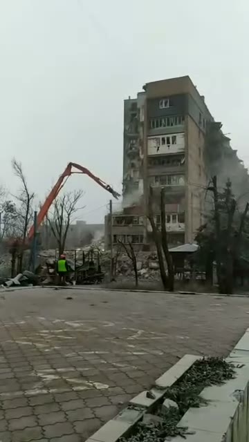 108 — long-reach excavator demolishing one entrance, rest of tower intact