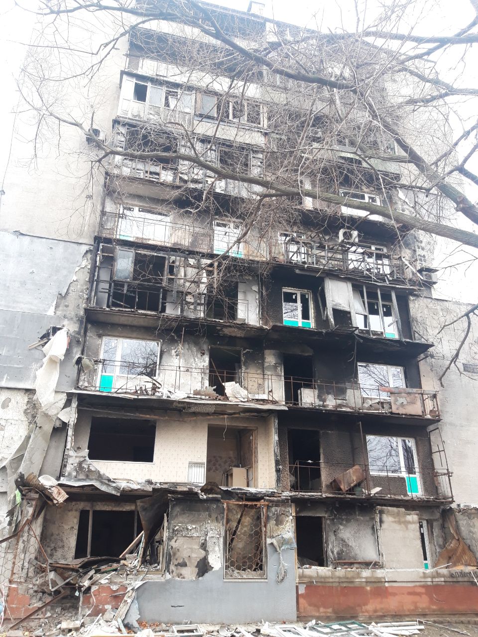 Fire-damaged balcony side of the building at Lenina Avenue 133, photographed 25 November 2022, showing extensive but non-collapse siege damage