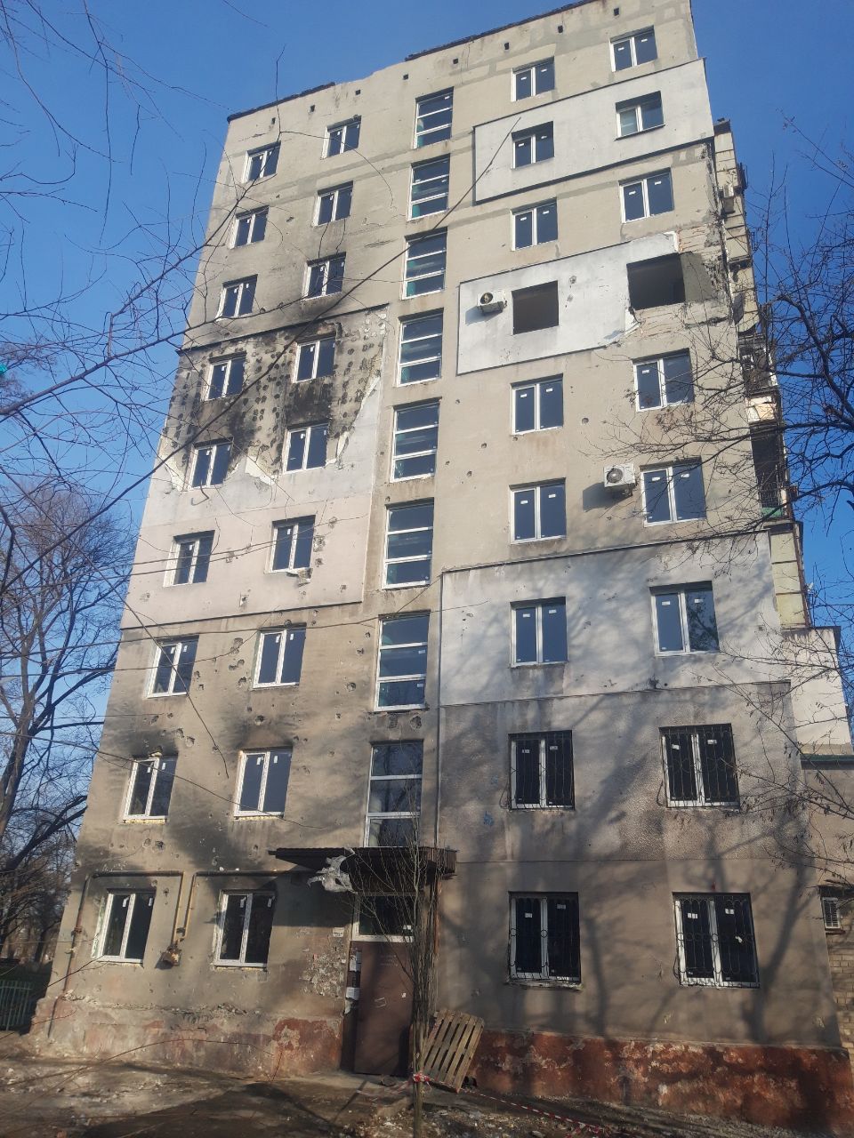 The same facade at Lenina Avenue 133, repaired with new windows and a renewed entrance canopy, photographed 10 December 2022 — one day after the project sign was posted
