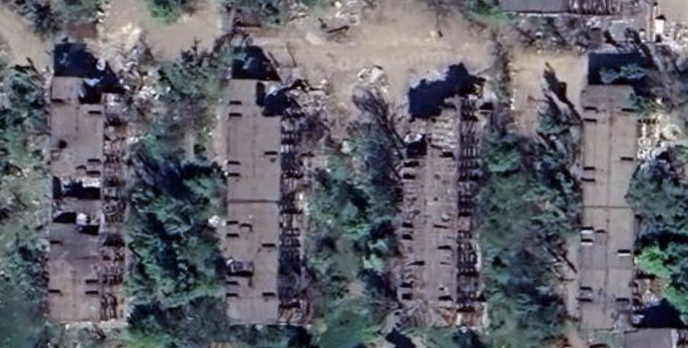 Satellite view of the same block in March 2022, showing roof and structural damage from the siege.